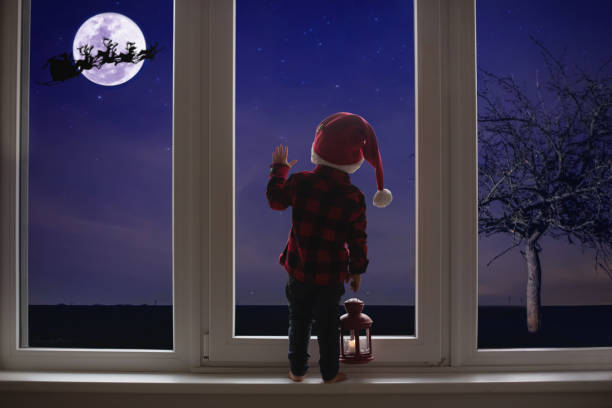 małe dziecko stojące przed dużymi francuskimi drzwiami, opierające się o to patrząc, trzymając latarnię - christmas window magic house zdjęcia i obrazy z banku zdjęć