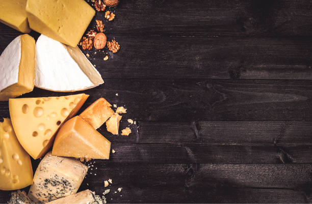 Various types of cheese on black wooden background with copy space Various types of cheese on black wooden background with copy space. Cheddar, parmesan, emmental, blu cheese. Top view, photo filtered in vintage style roquefort cheese stock pictures, royalty-free photos & images