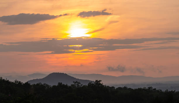 Sunrise over the mountain, with clouds and golden light in the sky, silhouette of tree, nature background.