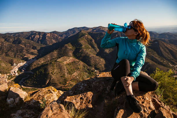 A hiker girl is drinking in the mountain