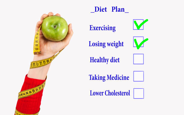 A food diary on a table surrounded by fruits and vegetables.