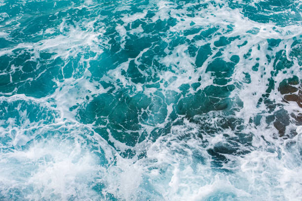 istock Turquoise sea surface background with splashing waves 1183562883