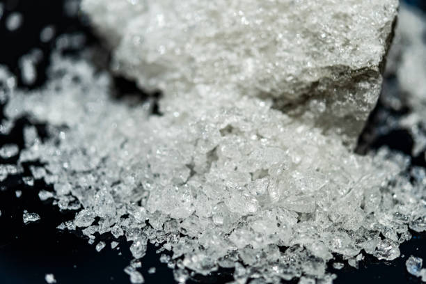 istock Large crystal of salt on black reflective surface; selective focus; natural edible salt 1183565250