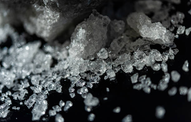 istock Large crystal of salt on black reflective surface; selective focus; natural edible salt 1183565388