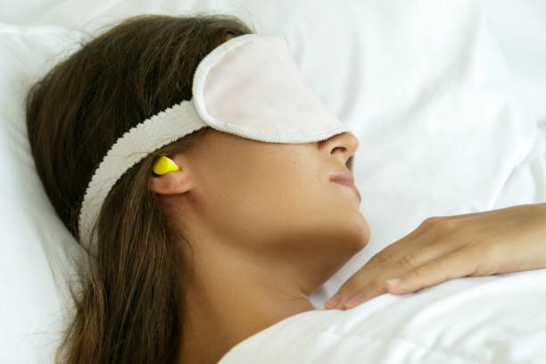 Woman is wearing eye mask and using earplugs stock photo