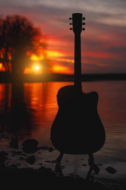 istock Guitar silhouette at sunset. Sea and trees on background. 1183569179