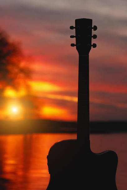 istock Guitar silhouette at sunset. Sea and trees on background. 1183569182