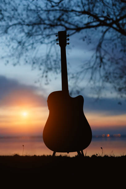 istock Guitar silhouette at sunset. Sea and trees on background. 1183569221
