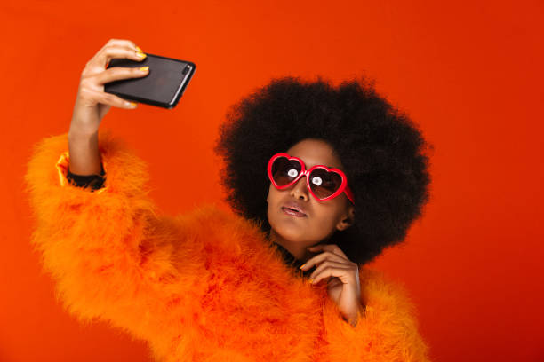 Beautiful afro woman Portrait of pretty afro american woman in a studio for a beauty session - Beautiful girl posing on colored background stylish selfie stock pictures, royalty-free photos & images