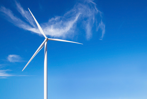 Molino de viento o turbina en rotación para generar energía eléctrica sobre fondo nublado y cielo photo