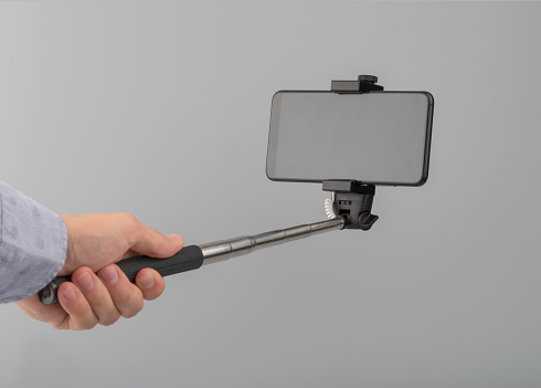 hand holds selfie stick with phone with screen clipping path