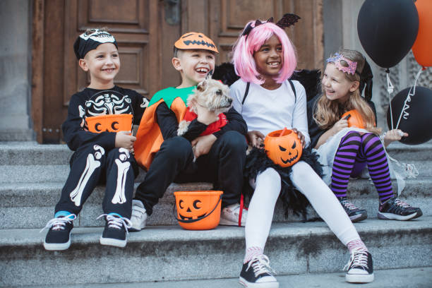 Trick or treat gang Multi ethnic group of children go for trick or treat, they wear costumes, and sitting on steps on doorway. Costumed pet dog is with them halloween costume stock pictures, royalty-free photos & images
