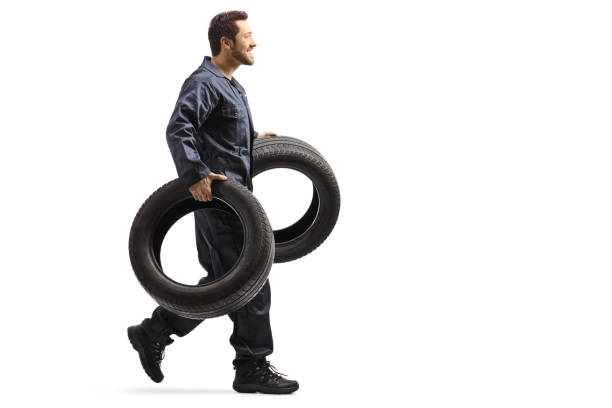 istock Auto mechanic walking and carrying tires 1183576950