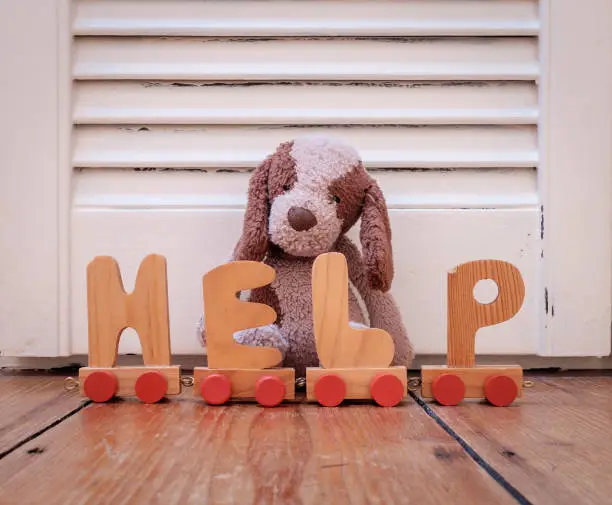 cuddly brown furry dog and toy letters making the word HELP. Concept for children in need