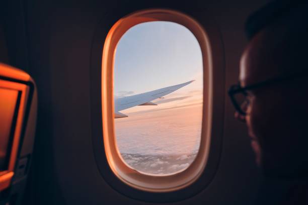 uomo che guarda attraverso il vindow di aereo - wing airplane window sunset foto e immagini stock