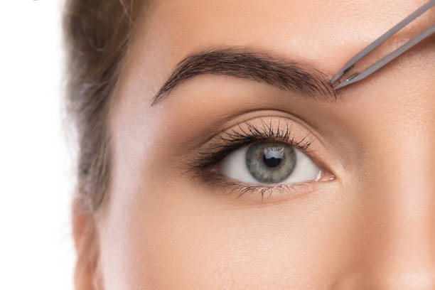 istock Woman tweeze eyebrows 1183585314