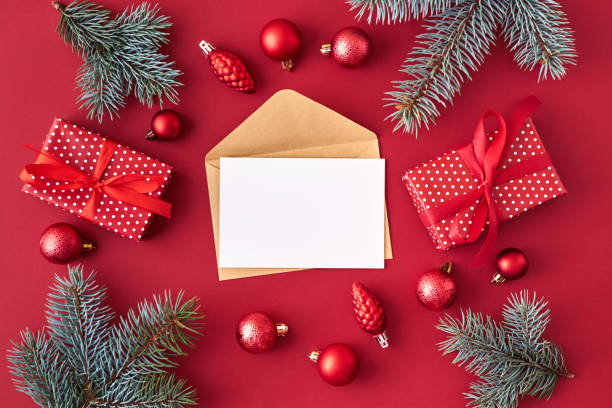 istock Mockup white greeting card and envelope with red christmas balls, spruce branches and gift box on a red background 1183586346