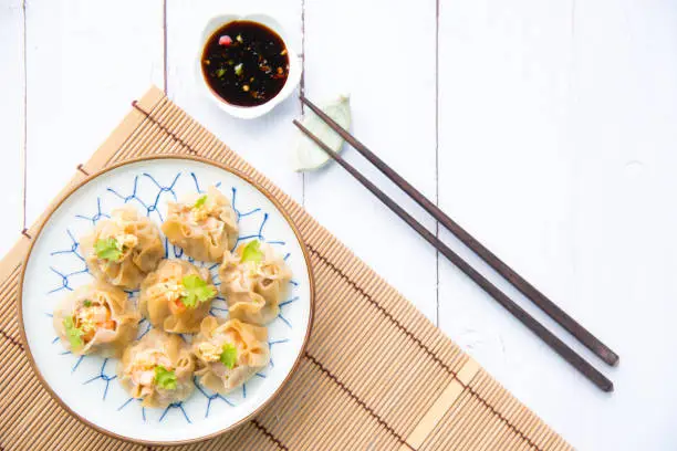 Traditional chinese steamed dumplings Dim Sums with sauce and chopsticks on light surface with copy space. Flat lay composition Asian food background.