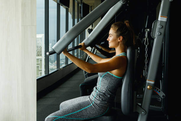 woman using press machine in the gym - body building determination deltoid wellbeing imagens e fotografias de stock