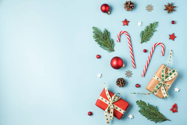 istock Christmas background. Fir tree branches, gift boxes, red decorations, candy, pine cones on blue background 1183596927