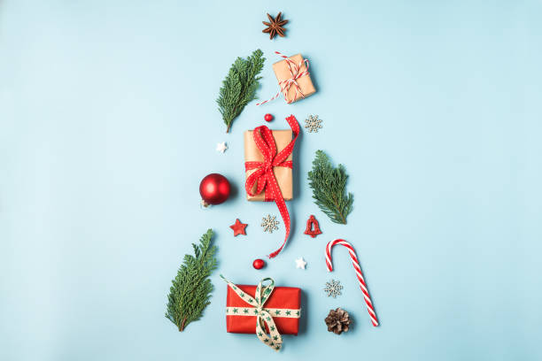 istock Christmas tree made from fir branches, winter decorations, candy and gift boxes on blue background 1183596934