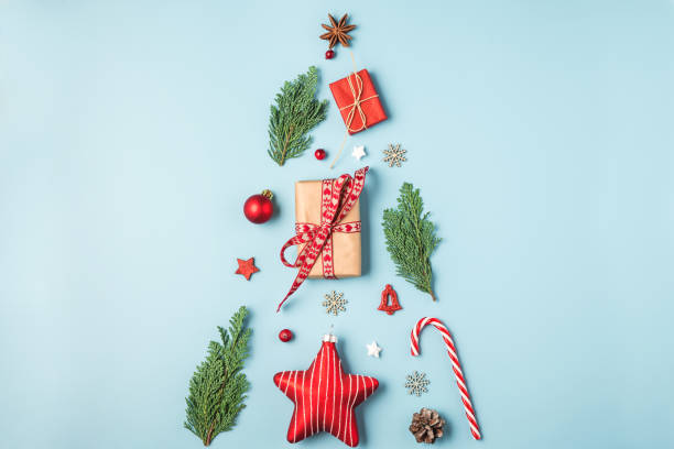 istock Christmas tree made from fir branches, red decorations, candy, winter berries and gift boxes on blue background 1183596939