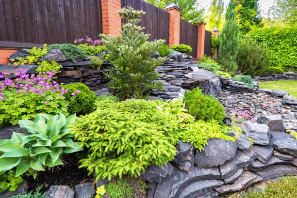 Natural stone landscaping in backyard in summer Landscape design of home garden close-up. Detail of beautiful landscaped garden with green plants, flowers and small waterfall. Natural stone landscaping in backyard in summer. garden designs stock pictures, royalty-free photos & images