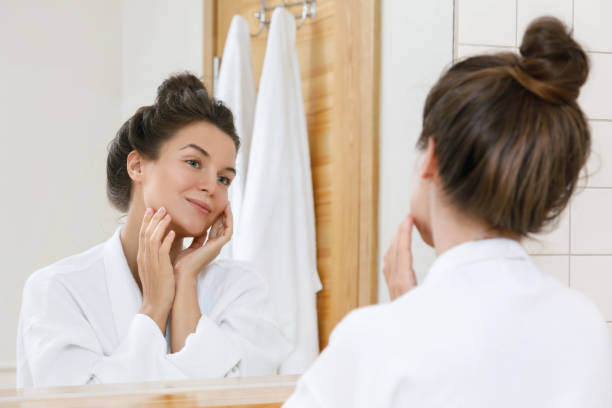 mujer joven mirándose al espejo - human face women mirror touching fotografías e imágenes de stock