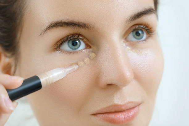 Woman using concealer stock photo