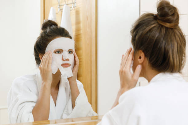 istock Woman is applying sheet mask on her face 1183600572