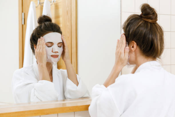istock Woman is applying sheet mask on her face 1183601150