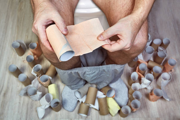 istock One man sits on a WC with toilet paper in hands. 1183601241