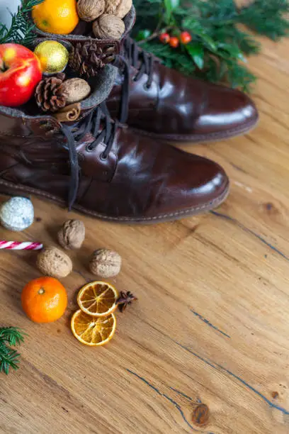 Blankly cleaned boots with sweets, nuts and apples to santa nikolaus gift, wooden floor