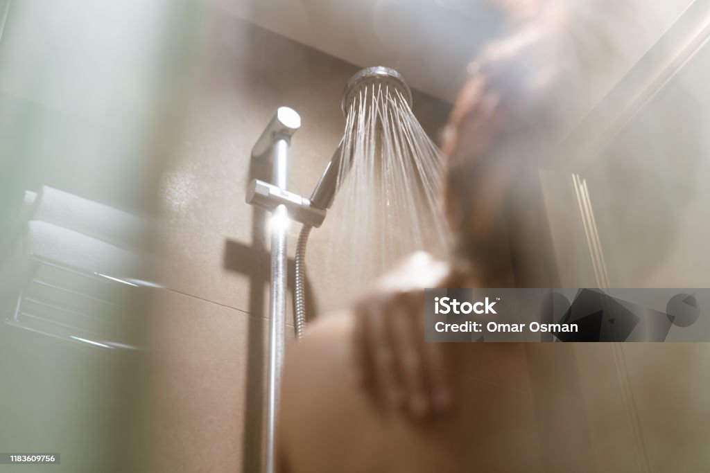 Young Asian woman taking a shower in the bathroom with hot steam filling the room - Lifestyle, bathe and hygiene concept Young diverse woman taking a shower in the bathroom and getting ready for work - Millennial girl showering with hot steam filling the room - Lifestyle, bathe and hygiene concept Shower Stock Photo