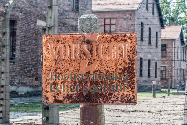 Electrified fence warning sign at Auschwitz I, Former German Nazi Concentration and Extermination Camp. Oswiecim, Poland - July 28, 2019: Electrified fence warning sign at Auschwitz I, Former German Nazi Concentration and Extermination Camp. ethnic cleansing stock pictures, royalty-free photos & images