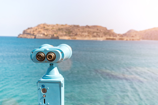 Coin operated binocular looking to the sea and Spinalonga Island on Crete, Greece.