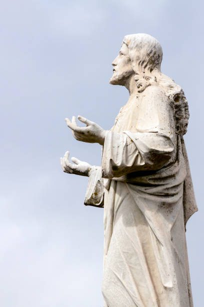 istock Old staue of Jesus Christ, side view, sky background with copy space 1183642179