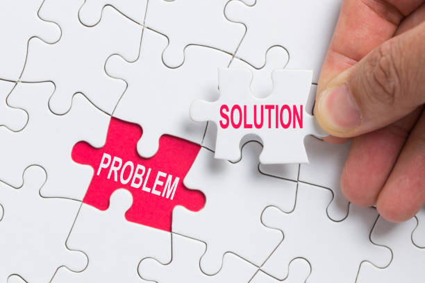 Hand holding piece of jigsaw puzzle with word problem and solution. stock photo