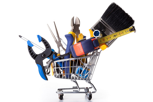 mix of construction tools inside a shopping cart (isolated on white)