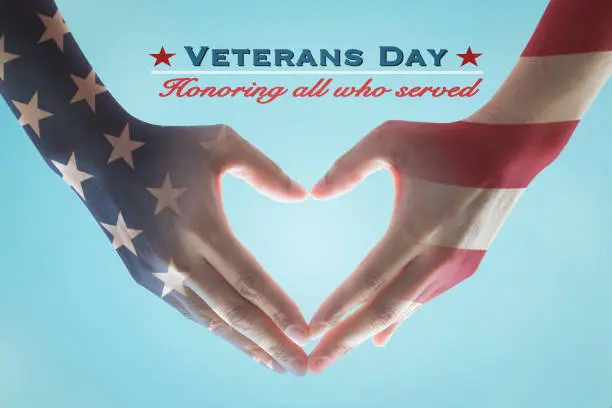 Photo of USA Veterans day with United Stated of America flag pattern on people's hands in heart shape and greeting announcement honoring all who served American country