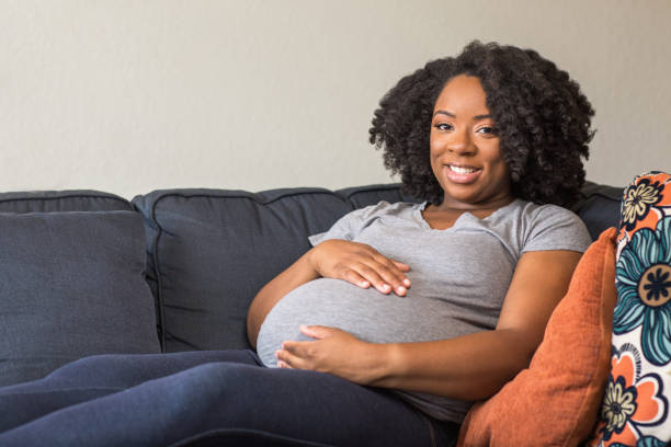 African American Pregnant Woman Sitting On A Sofa stock photo