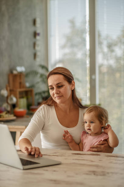 istock Baby girl cuddling with her mother while she is using laptop 1183657082