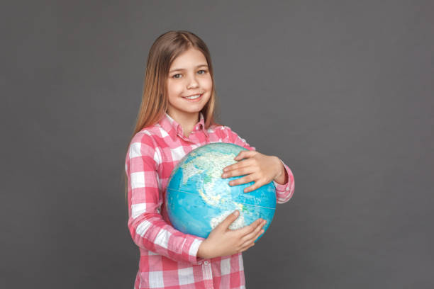istock Freestyle. Girl standing isolated on grey hugging globe smiling joyful 1183657213