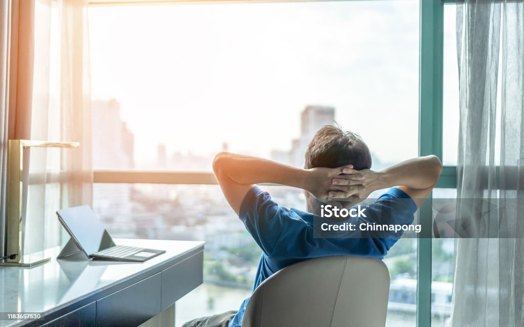 Life-work balance and city living lifestyle concept of business man relaxing, take it easy in office or hotel room resting with thoughtful mind thinking of life quality looking forward to cityscape Relaxation Stock Photo