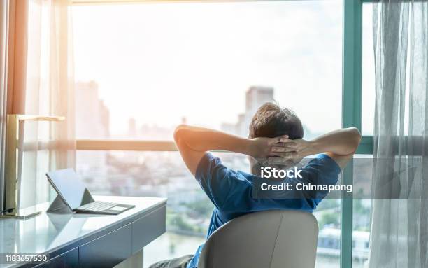 Lifework Balance And City Living Lifestyle Concept Of Business Man Relaxing Take It Easy In Office Or Hotel Room Resting With Thoughtful Mind Thinking Of Life Quality Looking Forward To Cityscape Stock Photo - Download Image Now