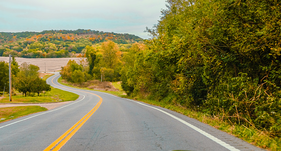 View of curvy road in Mid-Missouri in autumn; colorful hilly area in background