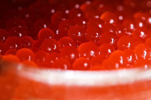 Glass jar with red caviar on a wooden surface. Largest species. Horizontal photography