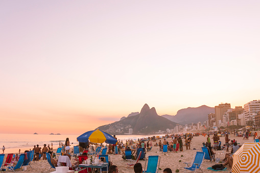 Rio de Janeiro, Brazil - September 23, 2018: View of locals and tourists enjoying the winter sunset at famous Ipanema beach in Rio de Janeiro, Brazil.