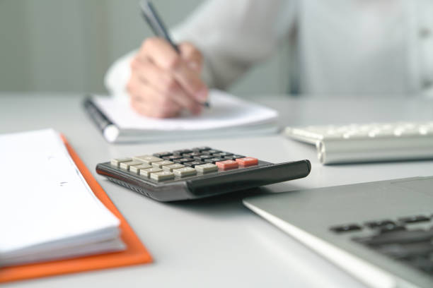 istock Office table view with Accountant at the background and focus on the calculator 1183689364