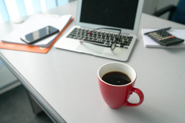 istock Office table view with laptop, cell phone, spectacles and focus on red coffee mug 1183689381